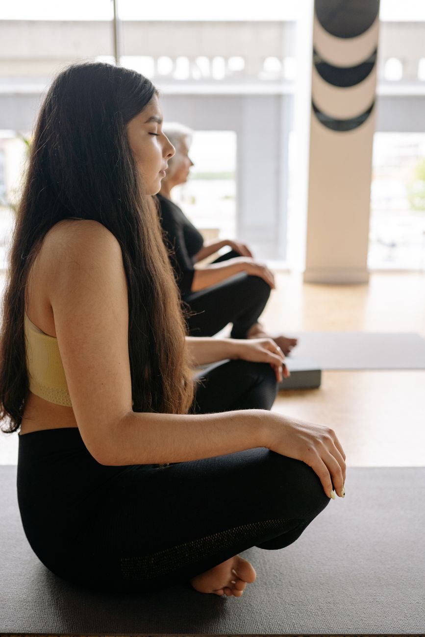 Woman practicing yoga meditation indoors with eyes closed for mindfulness and relaxation.