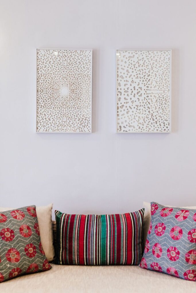 Interior with colorful throw pillows and minimalist artworks on white walls.